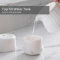 Water being poured from a jug into the small ultrasonic cool mist humidifier resting on a marble counter