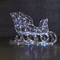 NOMA Pre-Lit 3.25 Ft Iridescent Sleigh with 105 Cool White LED Bulbs. Sleigh is Lit in Image. Dark Grey Wall Background.