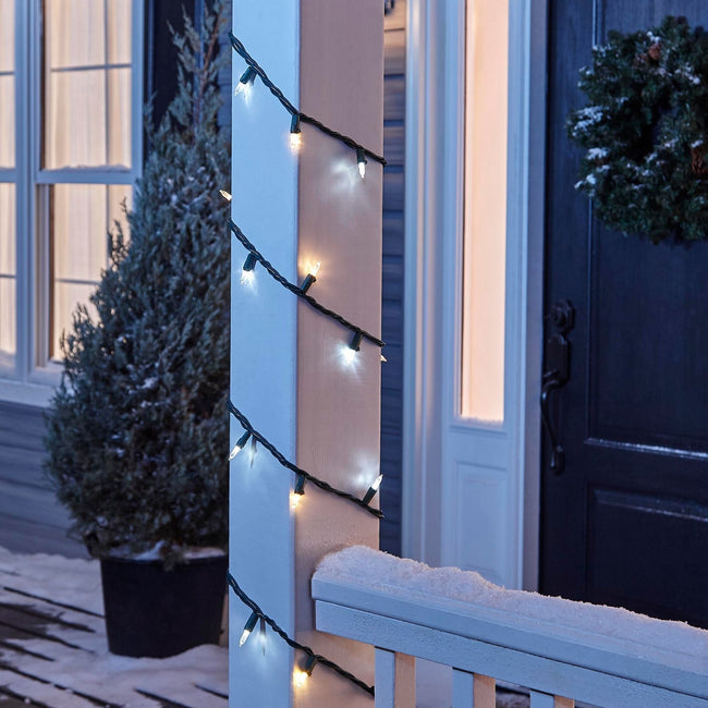 NOMA Warm & Pure White Mini LED String Lights, Wrapped Around Porch Pillar. In background: Potted Tree, and Wreath on Door