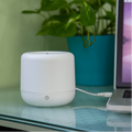 Small humidifier resting on a desk being charged by the USB port of a computer