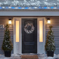 Noma C6 Blue & Pure White String Lights, on a roof edge above home entrance. Wreath on door and two potted trees on porch