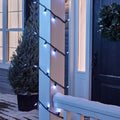 NOMA Cool White Mini LED String Lights, Wrapped Around Porch Pillar. In background: Potted Tree, and Wreath on Door