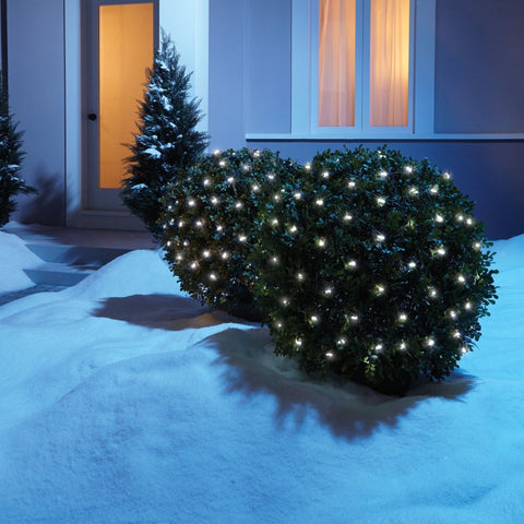 NOMA Mini 100 Count LED Pure White Net Lights displayed on a round shrub in a outdoor snow setting